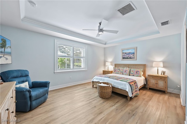 bedroom featuring light wood-type flooring, visible vents, and a raised ceiling