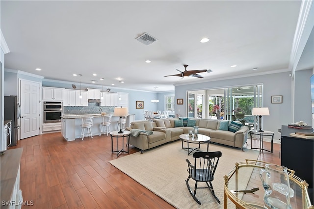 living room featuring ornamental molding, visible vents, and wood finished floors