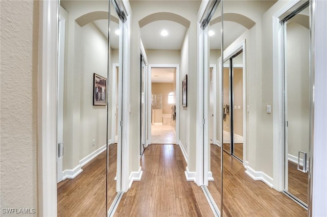 10731 Wintercress Dr, Estero, FL 34135 - hallway with baseboards, light wood-type flooring, and arched walkways