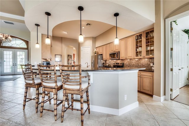 10731 Wintercress Dr, Estero, FL 34135 - kitchen with french doors, tasteful backsplash, a kitchen bar, appliances with stainless steel finishes, and arched walkways