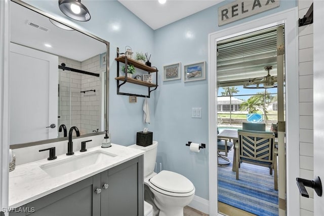 bathroom with toilet, vanity, a shower stall, and visible vents