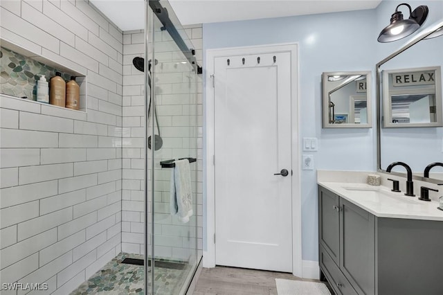 bathroom featuring a shower stall, wood finished floors, and vanity