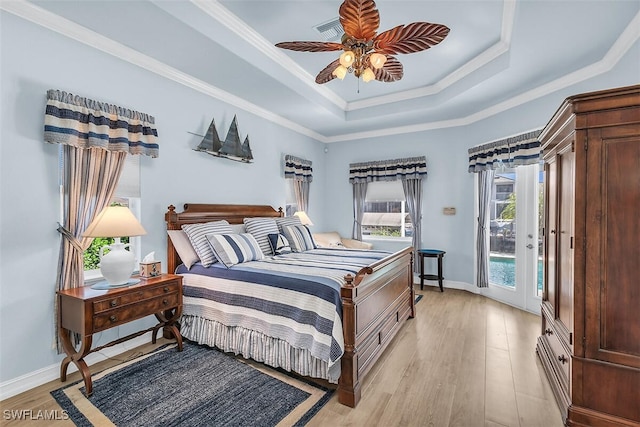 bedroom with ornamental molding, a tray ceiling, access to outside, and light wood-style flooring