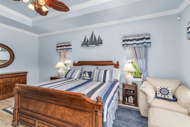 bedroom with ornamental molding, a tray ceiling, ceiling fan, and wood finished floors