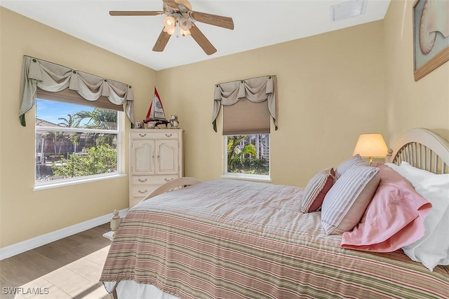 bedroom with light wood-style floors, baseboards, visible vents, and ceiling fan