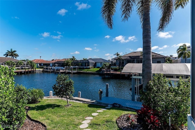 view of dock with a residential view, a water view, and a lawn