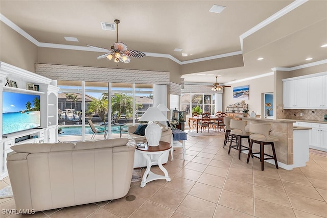 living area with ceiling fan, ornamental molding, light tile patterned flooring, and visible vents