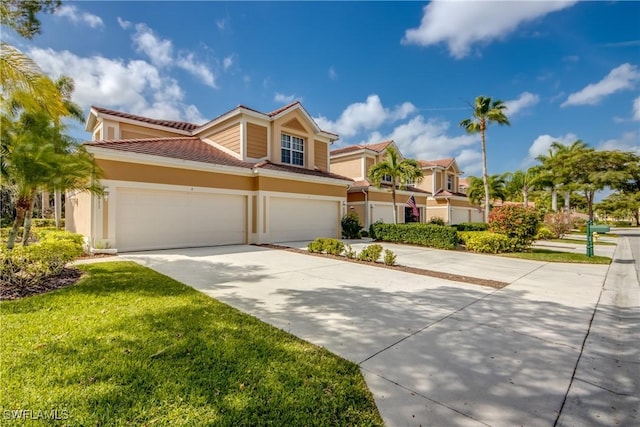 townhome / multi-family property with a tile roof, stucco siding, an attached garage, a front yard, and driveway