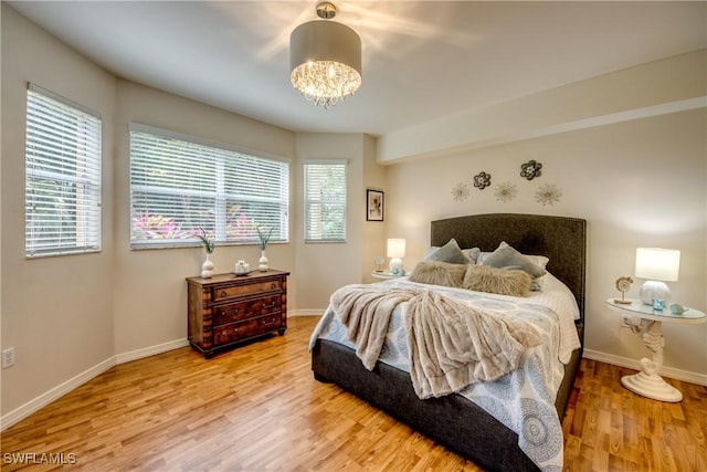 bedroom with a notable chandelier, wood finished floors, and baseboards