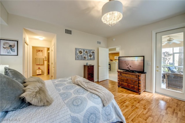 bedroom featuring access to outside, visible vents, light wood-style flooring, and an inviting chandelier