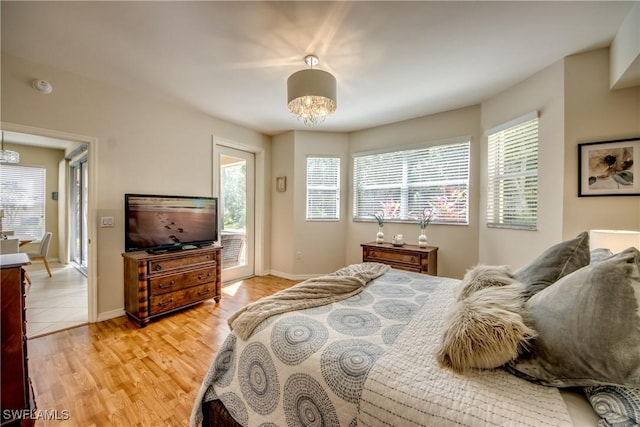 bedroom with light wood-type flooring, baseboards, and an inviting chandelier