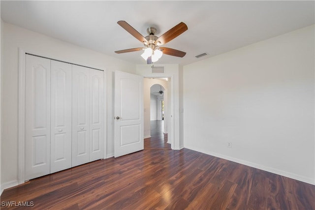 unfurnished bedroom featuring a ceiling fan, a closet, visible vents, and dark wood finished floors