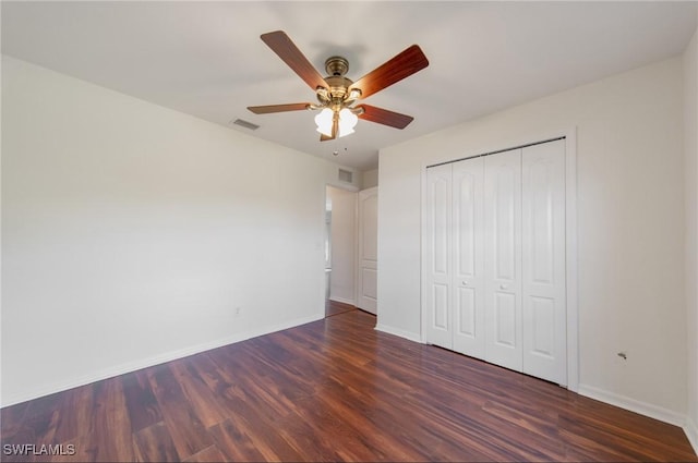 unfurnished bedroom featuring dark wood finished floors, a closet, visible vents, a ceiling fan, and baseboards