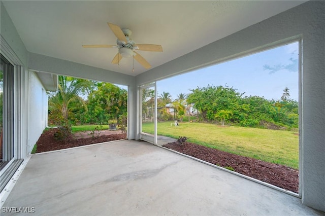 unfurnished sunroom featuring a ceiling fan and a healthy amount of sunlight