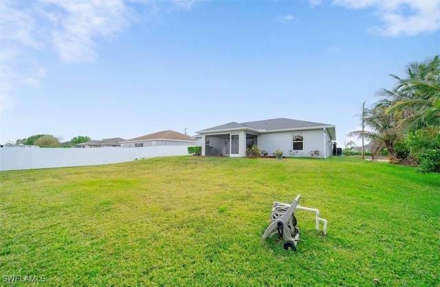 rear view of property with fence and a lawn