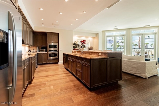 kitchen featuring light wood-style floors, stainless steel appliances, dark brown cabinets, and french doors