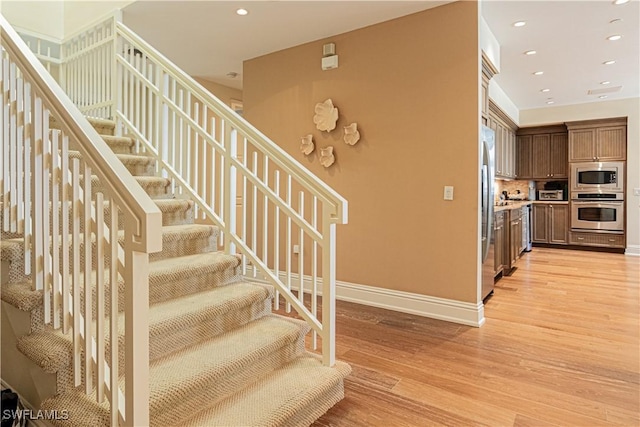 stairway featuring recessed lighting, baseboards, and wood finished floors