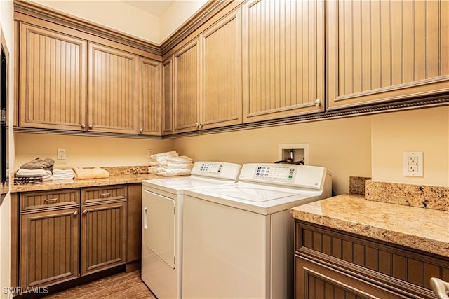 laundry room with cabinet space, light wood-style flooring, and washer and clothes dryer