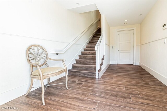 interior space featuring baseboards, stairway, and wood finished floors