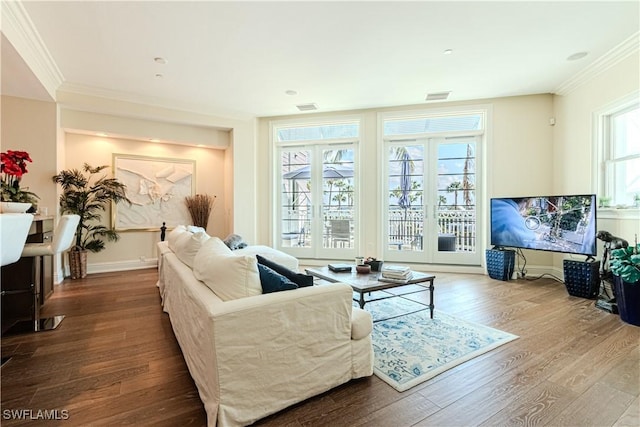 living area with ornamental molding, visible vents, baseboards, and wood finished floors