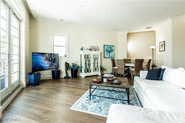 living area featuring visible vents, crown molding, baseboards, and wood finished floors