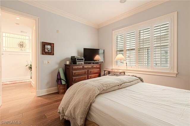 bedroom featuring ornamental molding, baseboards, and wood finished floors