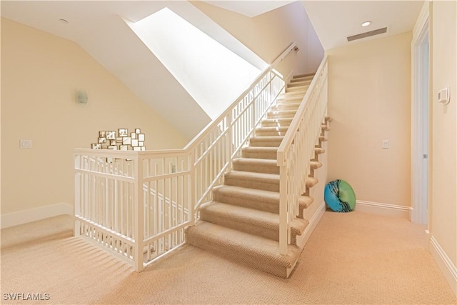 staircase with vaulted ceiling, carpet, visible vents, and baseboards