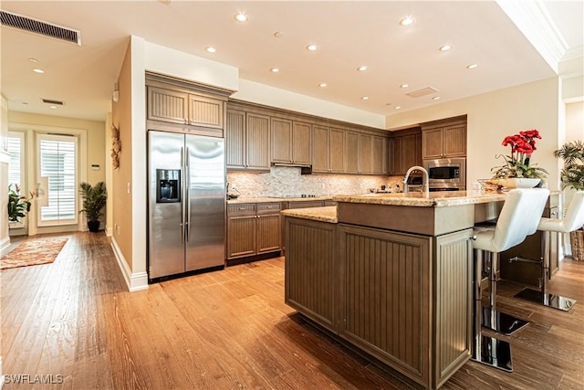 kitchen featuring appliances with stainless steel finishes, visible vents, light wood-style floors, and tasteful backsplash