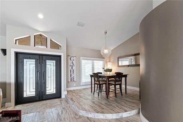 foyer with visible vents, baseboards, vaulted ceiling, light wood-style floors, and an inviting chandelier