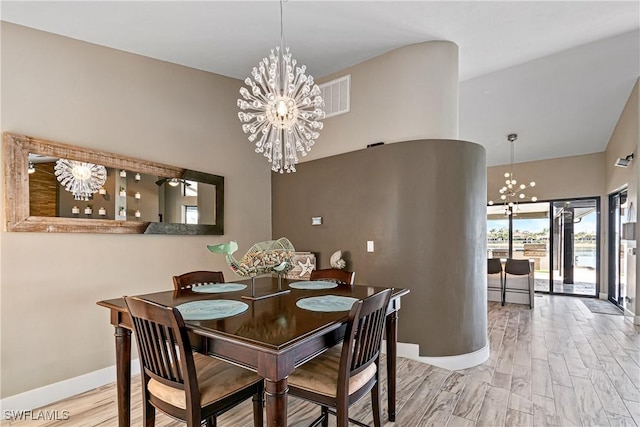 dining area featuring visible vents, a notable chandelier, baseboards, and wood finished floors