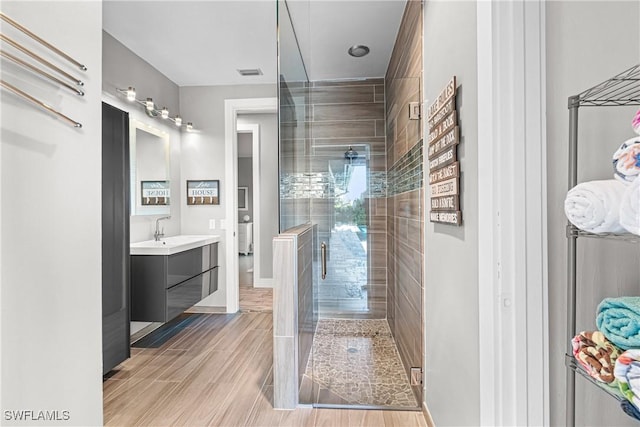 full bathroom featuring visible vents, toilet, a stall shower, wood tiled floor, and vanity