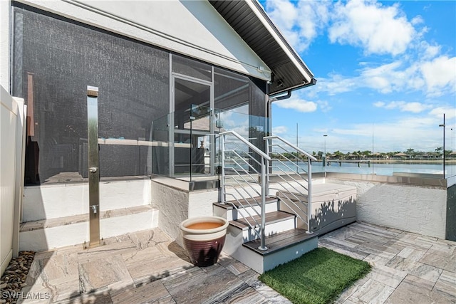 view of patio with a water view and a sunroom