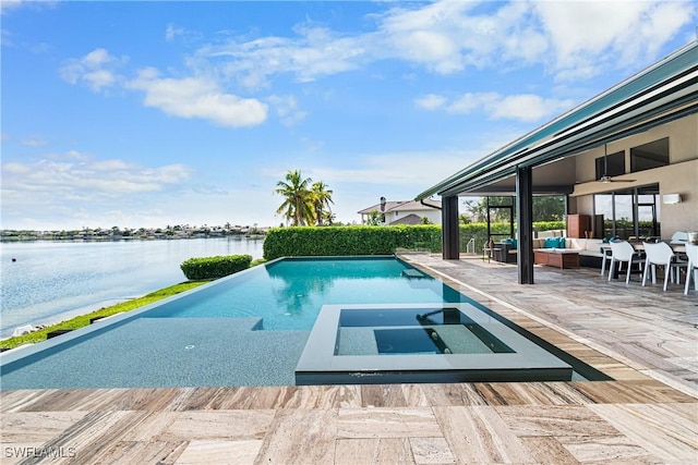 view of pool with a pool with connected hot tub, a water view, a patio, and an outdoor living space