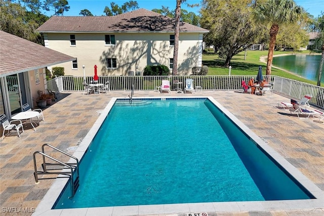 pool featuring a water view, a patio, and fence