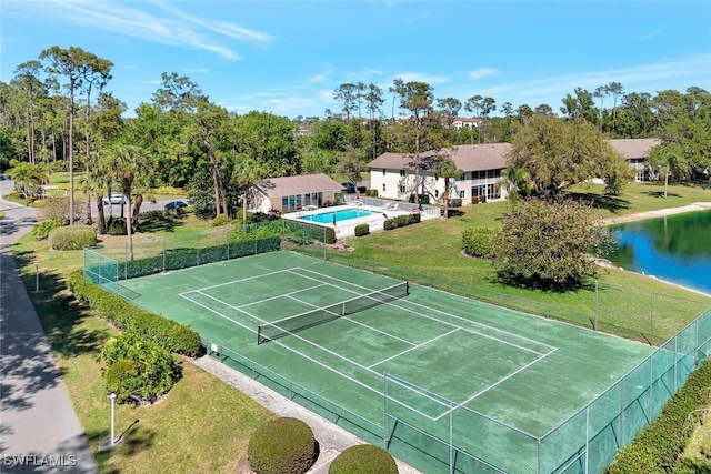 view of tennis court featuring a yard, fence, and a water view