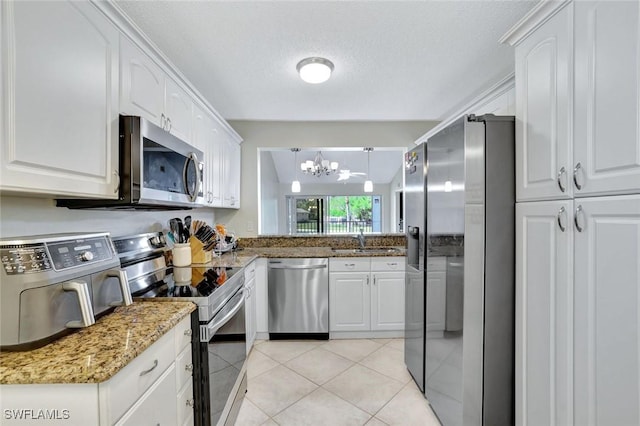 kitchen with a notable chandelier, a sink, stainless steel appliances, white cabinets, and light tile patterned flooring