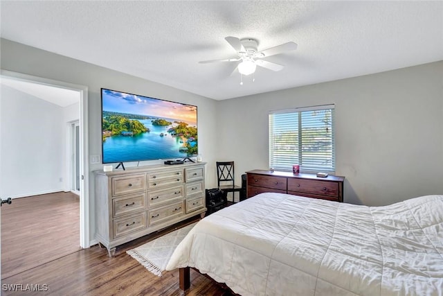 bedroom with baseboards, a textured ceiling, ceiling fan, and dark wood-style flooring