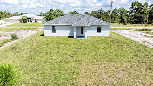 view of front of house with stucco siding, roof with shingles, and a yard