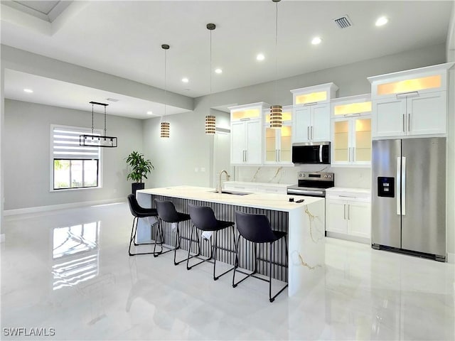 kitchen with stainless steel appliances, a sink, visible vents, white cabinets, and a kitchen breakfast bar