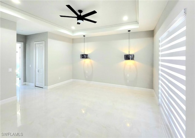 empty room with a tray ceiling, recessed lighting, ceiling fan, concrete flooring, and baseboards