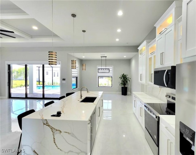 kitchen featuring recessed lighting, stainless steel appliances, a sink, white cabinets, and a center island with sink