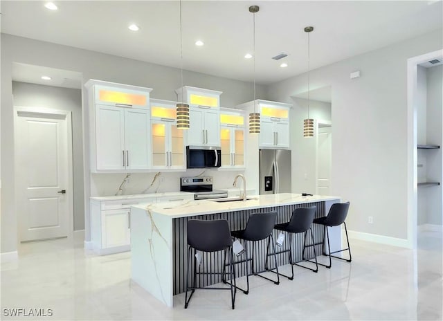 kitchen featuring a spacious island, glass insert cabinets, stainless steel appliances, a kitchen bar, and white cabinetry