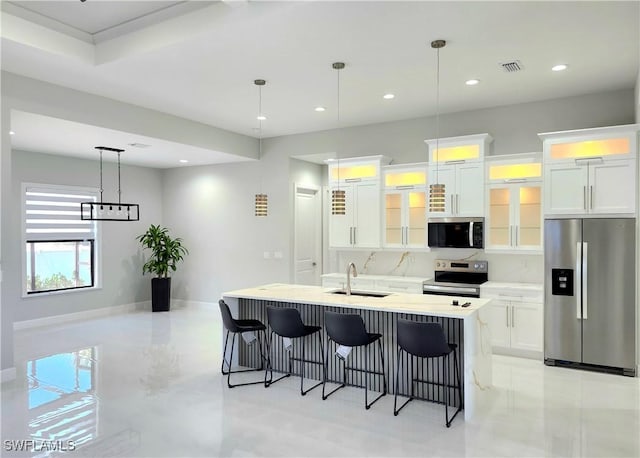 kitchen featuring visible vents, a kitchen breakfast bar, stainless steel appliances, white cabinetry, and a sink