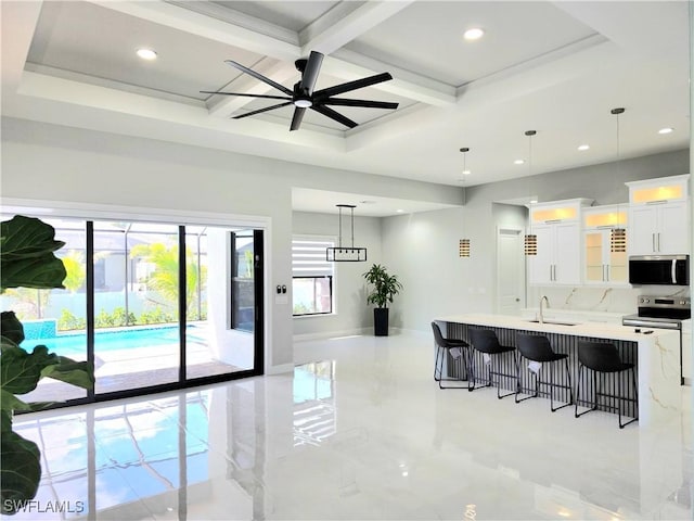 kitchen with a breakfast bar area, stainless steel appliances, coffered ceiling, a sink, and light countertops