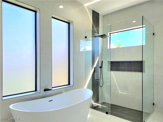 bathroom featuring a walk in shower and a freestanding bath