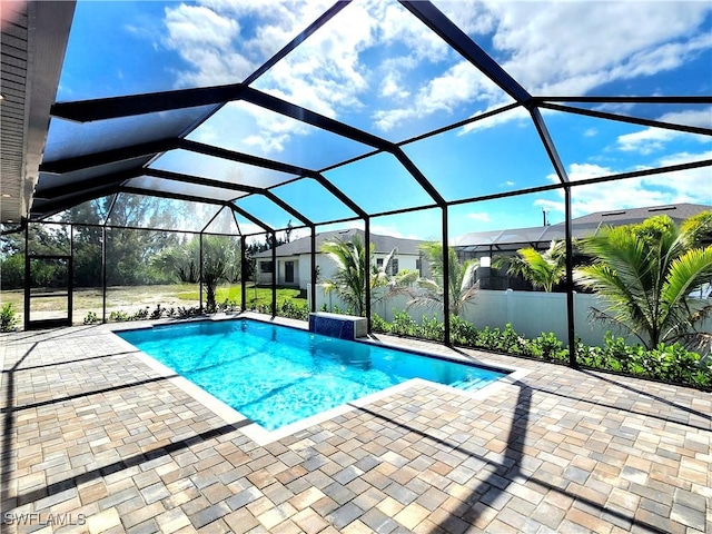 outdoor pool featuring glass enclosure and a patio area