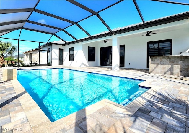 outdoor pool featuring a ceiling fan, glass enclosure, a patio, and outdoor dry bar