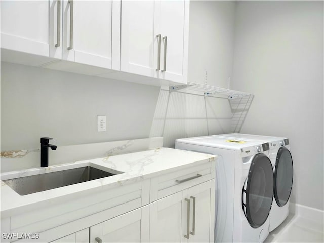 laundry area with washer and clothes dryer, a sink, and cabinet space