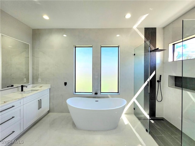 bathroom with marble finish floor, double vanity, a sink, a freestanding tub, and walk in shower