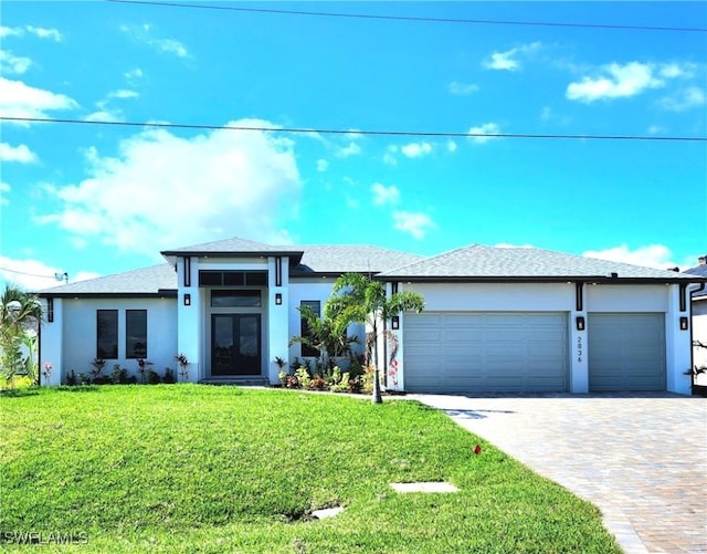 view of front of home with a garage, decorative driveway, a front yard, and stucco siding